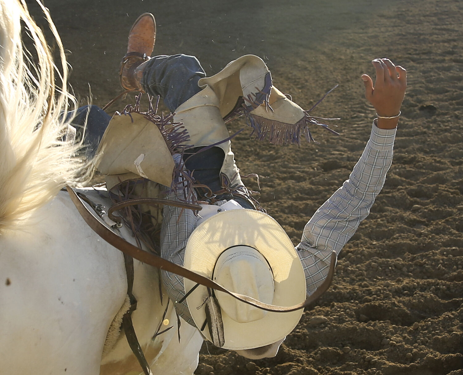 Micah Frasier falls back and to the right as the horse makes his second buck out